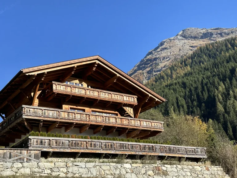Holzfassade und Balkone des Grand Chalets vor einem bewaldeten Berghang