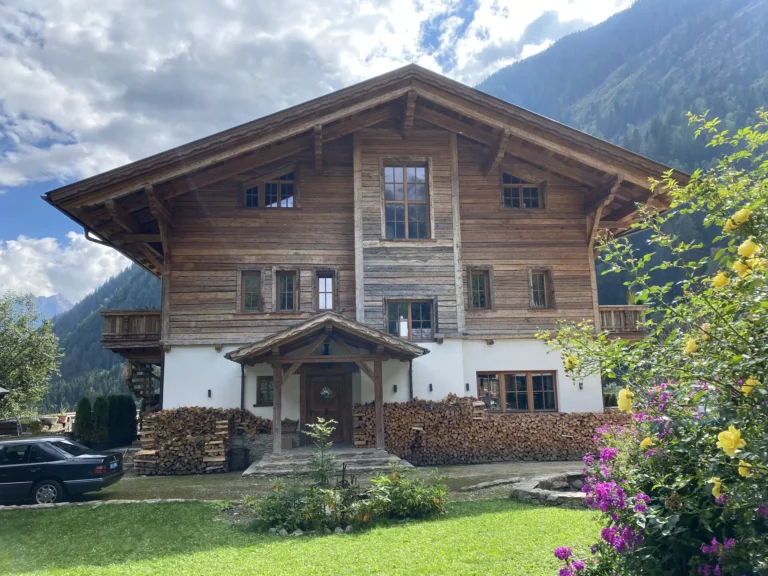 Hofseite des Grand Chalets mit Holzfassade und Garten im Sommer