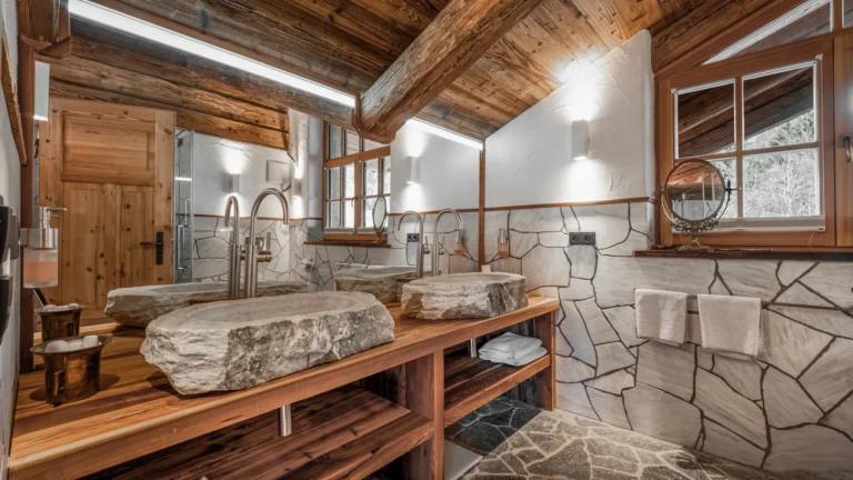 Bad mit zwei Natursteinwaschbecken, Holz und Dusche in der Panorama-Suite