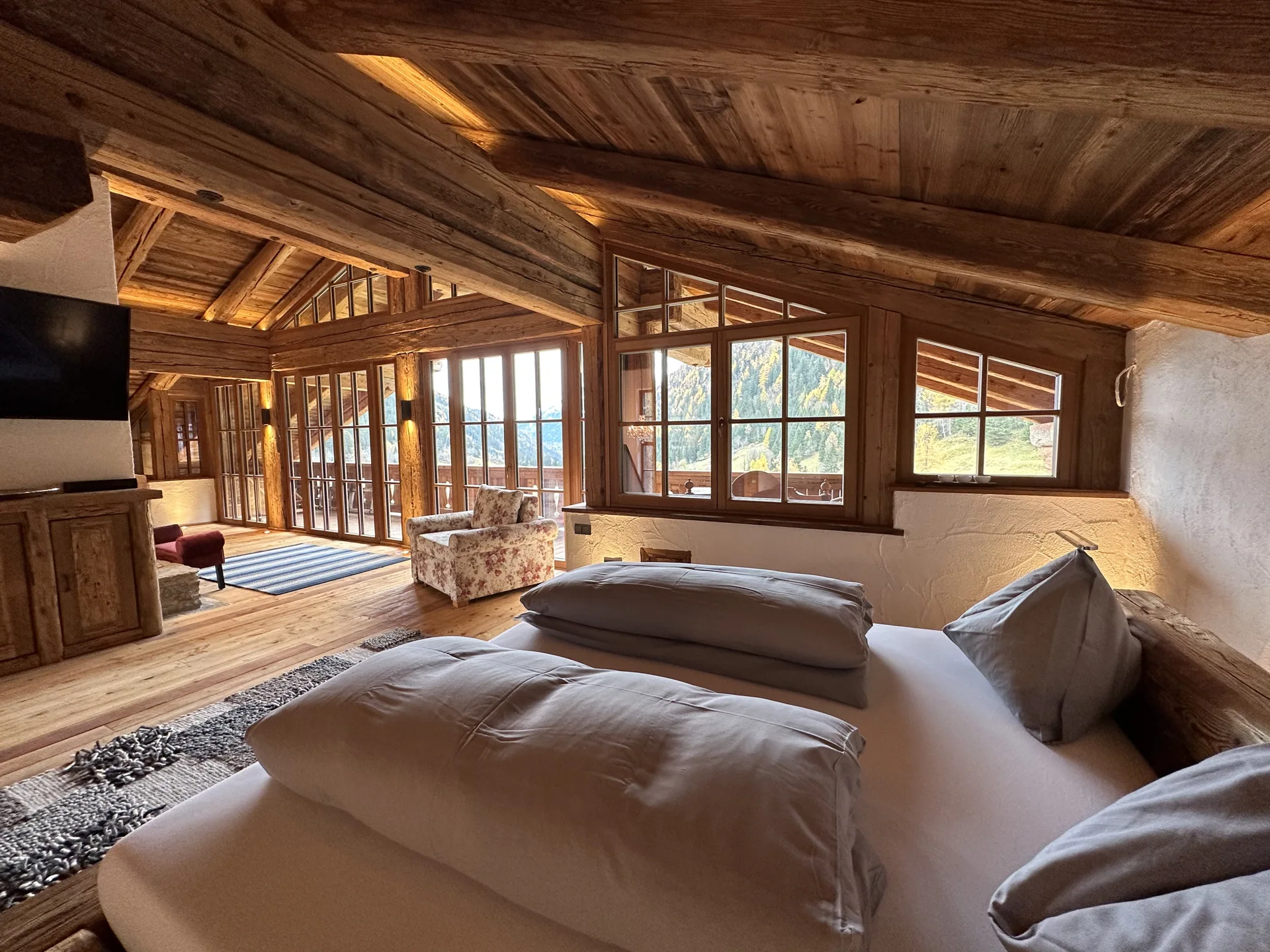 Bett und große Fensterfront mit Blick nach draußen in der Panorama-Suite