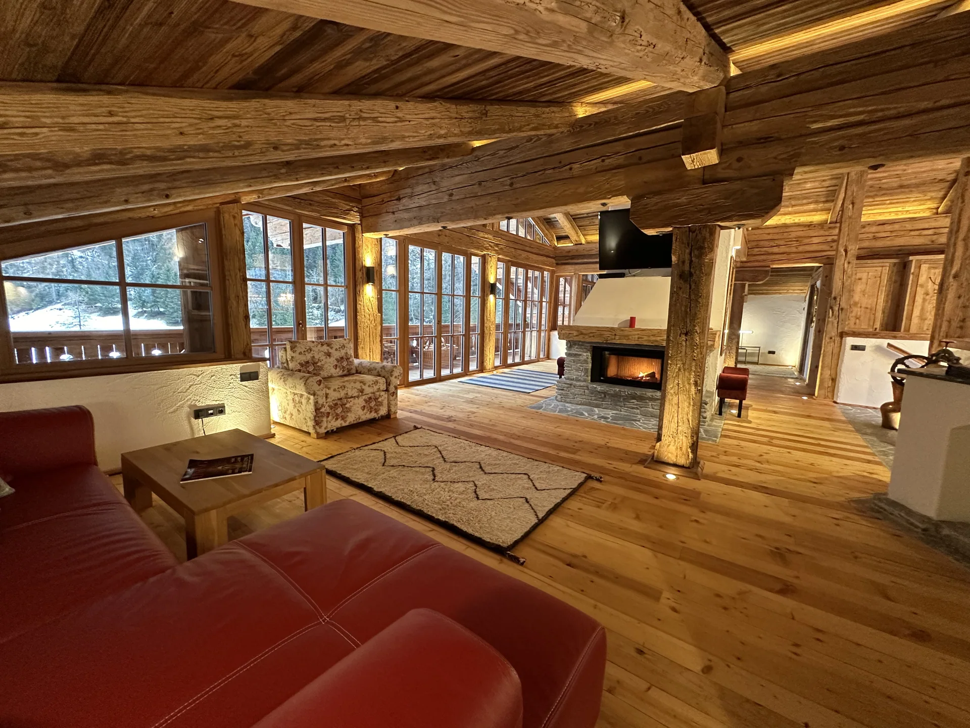 Wohnraum der Panorama-Suite mit Kamin, Holzdachstuhl und großer Fensterfront