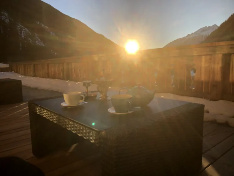 Tassen und Teekanne auf der verschneiten Studio-Terrasse im tief stehenden Sonnenlicht