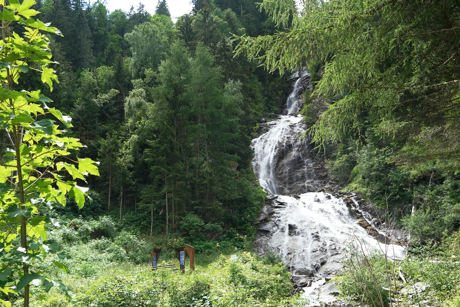Innerfraganter Wasserfall mit Alpe-Adria-Monument zwischen Bäumen und Felsen